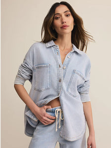  Woman wearing a light blue denim shirt and shorts on a beige background