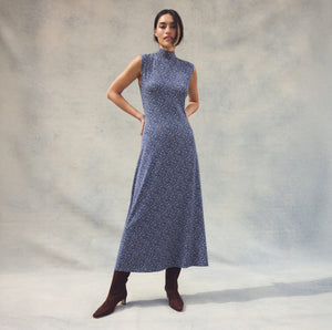  Woman wearing a blue patterned dress against a plain background