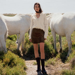  Woman standing between two white horses in a natural setting