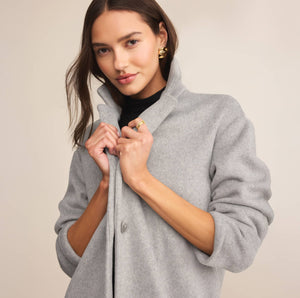  Woman wearing a gray coat against a plain background