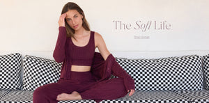  Woman in burgundy loungewear sitting on a checkered sofa with 'The Soft Life' text.