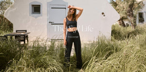  Woman standing outdoors with text overlay 'The So/ Life Shop Lounge' on a white building.