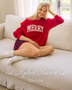  Woman wearing a red 'MERRY' sweatshirt sitting on a couch with text overlay.