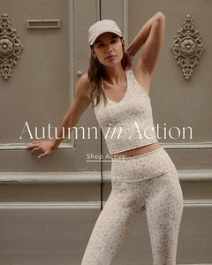 Woman in activewear posing in front of a decorative door with 'Autumn in Action' text.