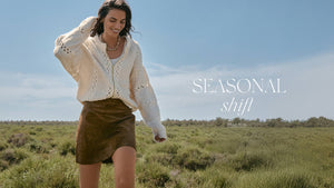  Woman in a white sweater and brown skirt standing in a field with 'SEASONAL shift' text overlay.