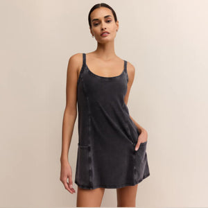  Woman wearing a black slip dress against a beige background