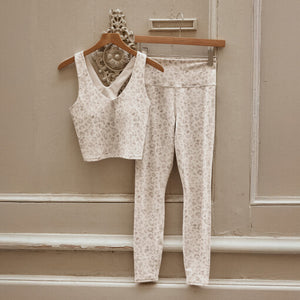  Floral-patterned top and pants on hangers against a beige wall.