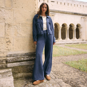 TopsSirena Rib Tank Woman in blue denim outfit standing in front of a stone building with arches.