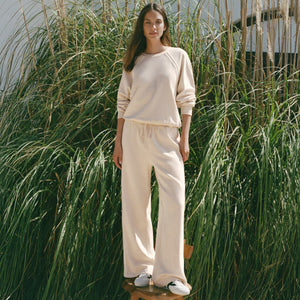  Woman in beige sweater and pants standing in tall grass