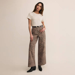 DressesMelbourne Sandy Bay Palm Midi Dress Woman wearing a white top and patterned pants on a beige background