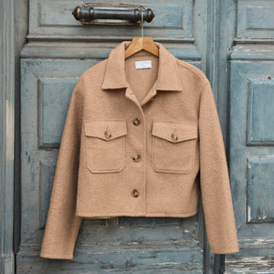 TopsSirena Rib Tank Beige jacket on a hanger against a rustic wooden door