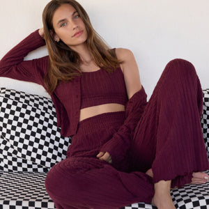 DressesCallahan Crochet Midi Dress Woman wearing a burgundy outfit sitting on a checkered couch.
