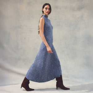 DressesMelbourne Sandy Bay Palm Midi Dress Woman wearing a blue patterned dress with brown boots against a neutral background