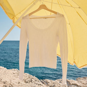 SweatersLooking Glass Crochet Polo Sweater White long-sleeve shirt on a hanger under a yellow umbrella with ocean view