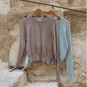 TopsSirena Rib Tank Two sweaters, one brown and one light blue, hanging on wooden hangers against a stone wall.
