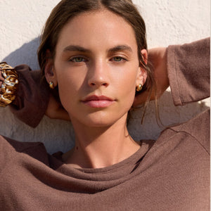  Woman wearing a brown top against a light background