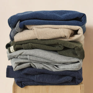 DressesMelbourne Sandy Bay Palm Midi Dress Stack of folded sweaters in various colors on a wooden surface.