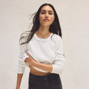 DressesMelbourne Sandy Bay Palm Midi Dress Woman wearing a white cropped sweater and black pants against a plain background