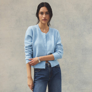  Woman wearing a light blue cardigan and jeans against a plain background
