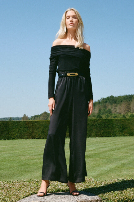 Woman wearing a black outfit with a belt in an outdoor setting