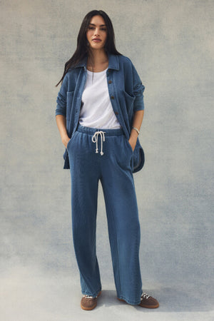Woman wearing a blue denim outfit with a plain background