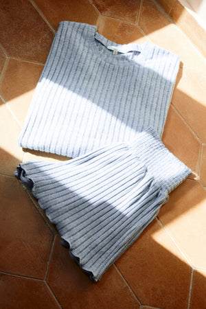 Folded gray ribbed sweater on a brown tiled floor
